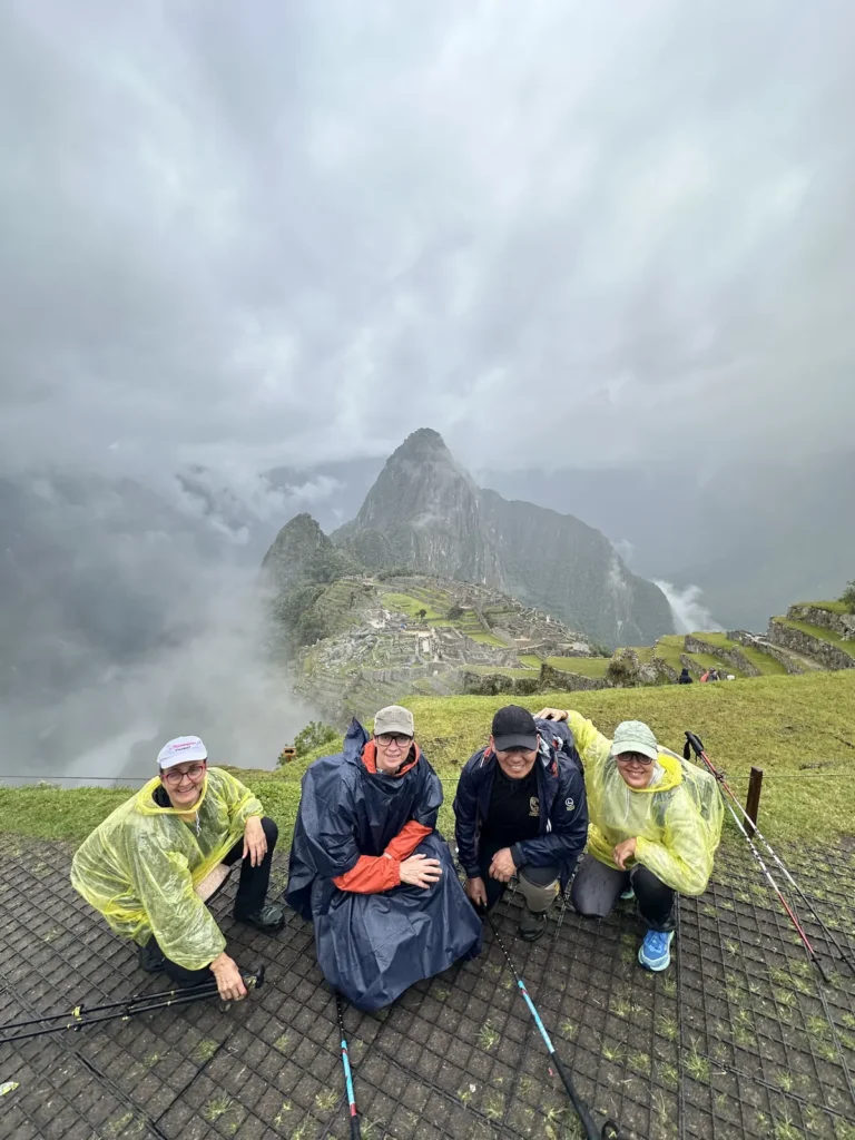Grupo con ponchos de lluvia frente a Machu Picchu entre las nubes