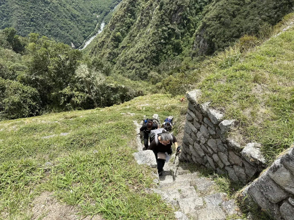 Caminante junto a un muro inca de Wiñay Wayna, con el cañón del Urubamba al fondo